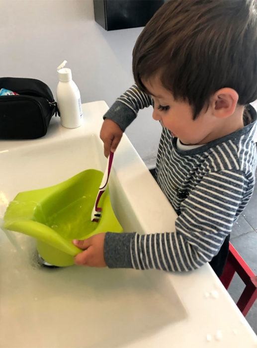 Niño lavando el orinal con el cepillo de dientes 