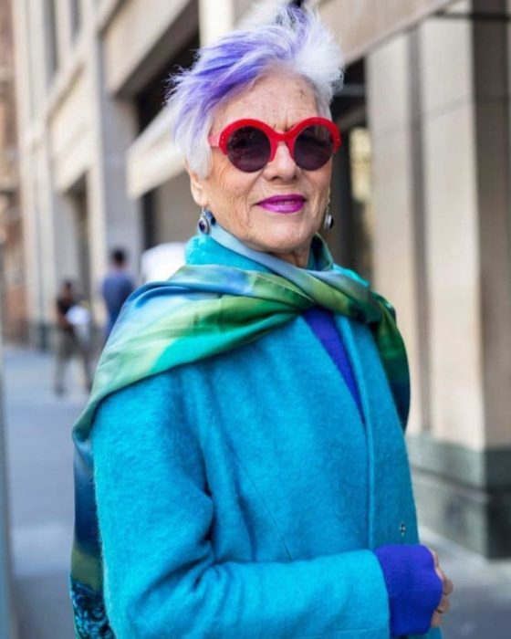 Mujer madura con saco azul y cabello corto canoso con mechón morado