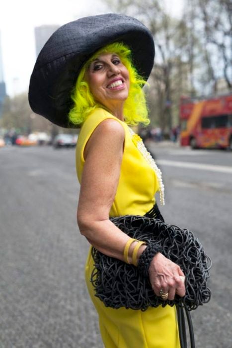 Mujer mayor con blusa amarilla y sombrero negro con cabello verde fosforescente 
