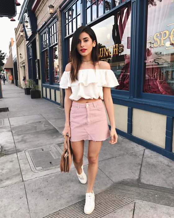 Chica usando un outfit inspirado en Lara Jean con una falda de color rosa, tenis y blusa blanca 