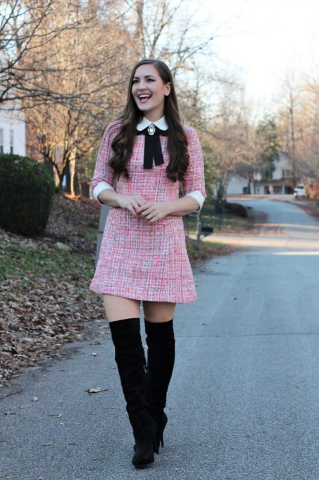 Chica usando un outfit inspirado en Lara Jean con vestido de cuadros color rosa y botas negras altas 