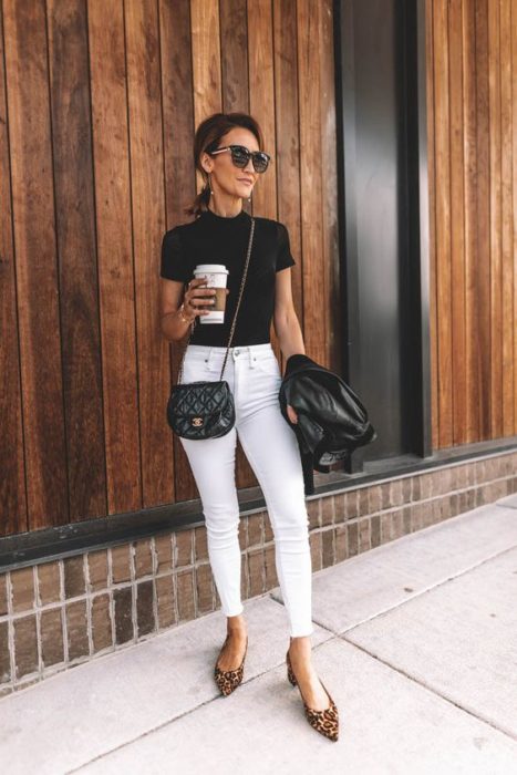 Mujer con cabello recogido y gafas obscuras usa blusa negra y pantalón blanco