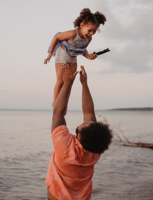 Frases del día del padre; papá jugando a lanzar a su hija en el aire