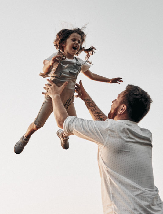 Frases del día del padre; papá jugando a lanzar a su hija en el aire