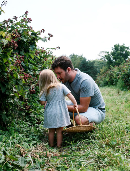 Frases del día del padre; papá e hija recolectando frutas de un huerto