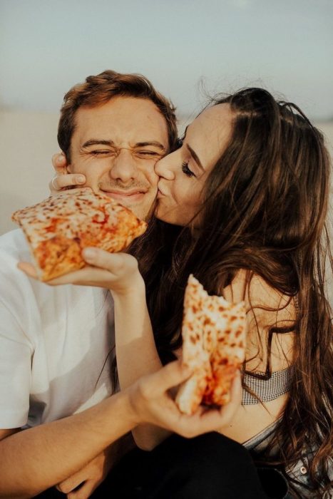 Pareja comiendo pizza y besándose