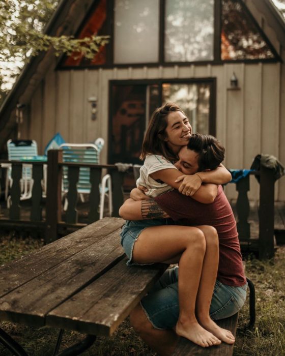 Pareja sentada en una mesa de madera abrazándose