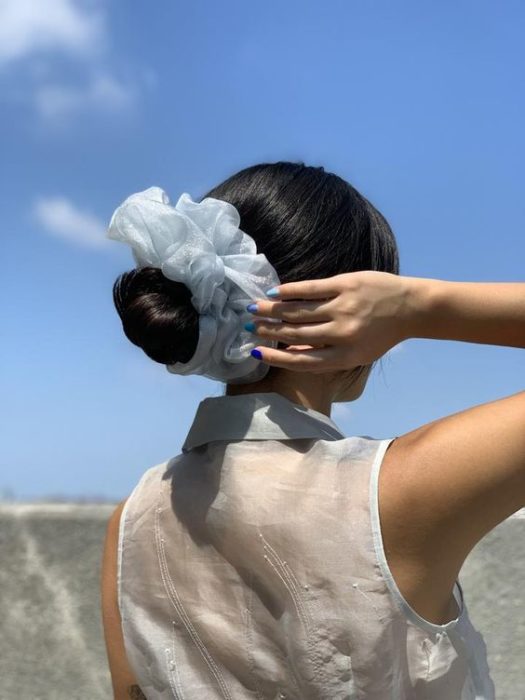 Chica con cabello negro en chongo y scrunchie gigante azul