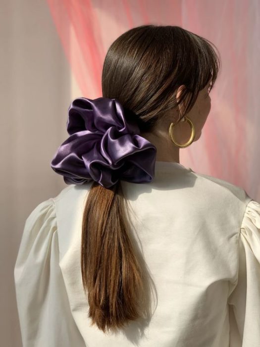 Chica de cabello largo castaño y scrunchie gigante morado