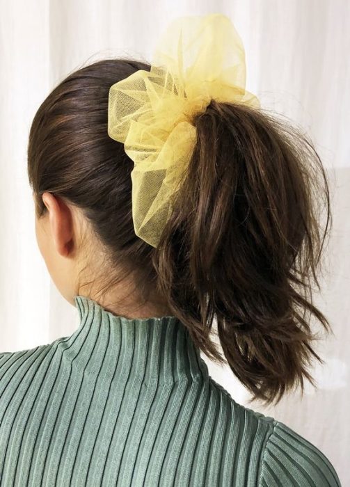 Chica con coleta alta y un scrunchie gigante amarillo