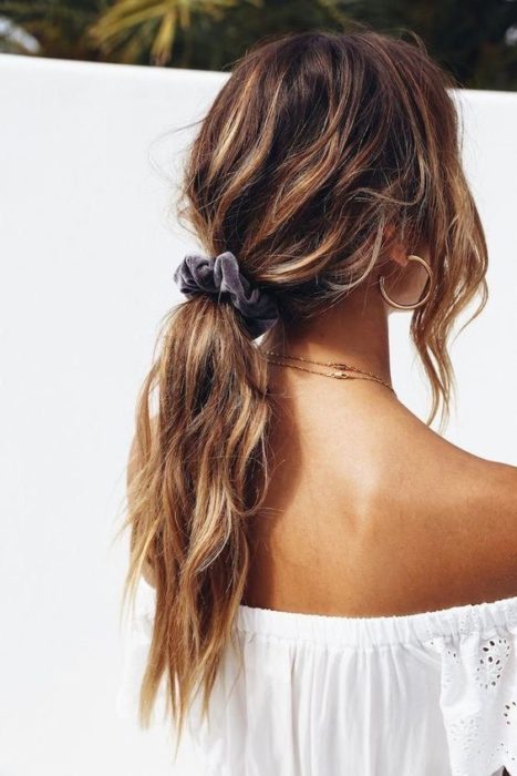 Chica con coleta baja despeinada con una scrunchie