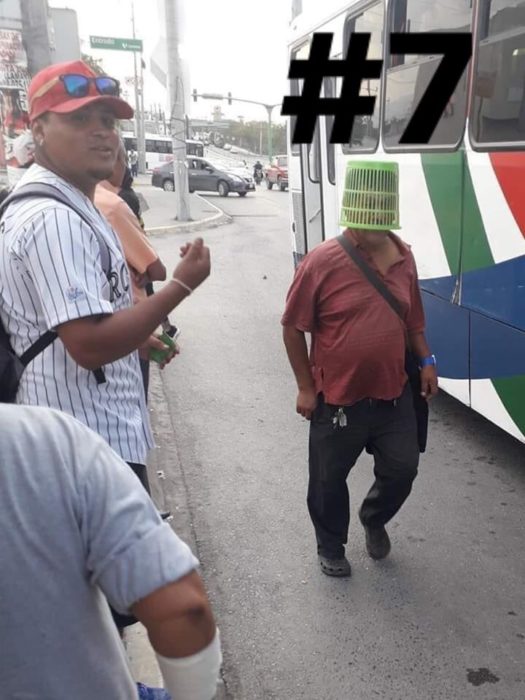 Señor usando un bote de basura en la cabeza mientras camina por la calle 