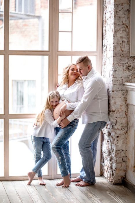 Familia posando para una foto en la que la esposa está embarazada