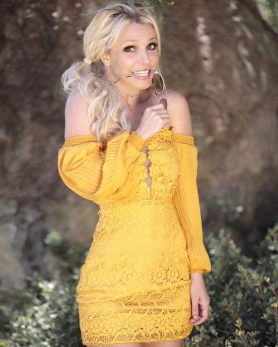 Britney Spears usando un vestido off the shoulder corto color mostaza