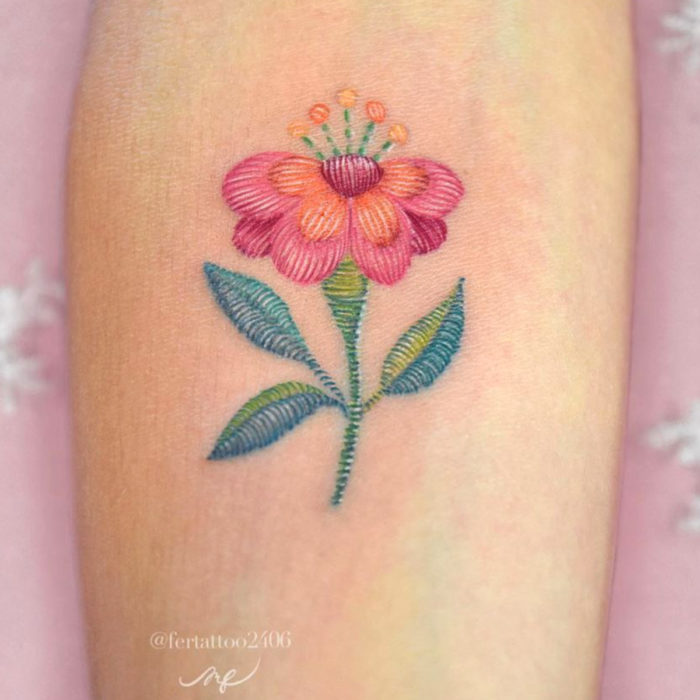 Fernanda Ramírez, tatuadora mexicana crea tatuajes bordados; flor rosa en el brazo