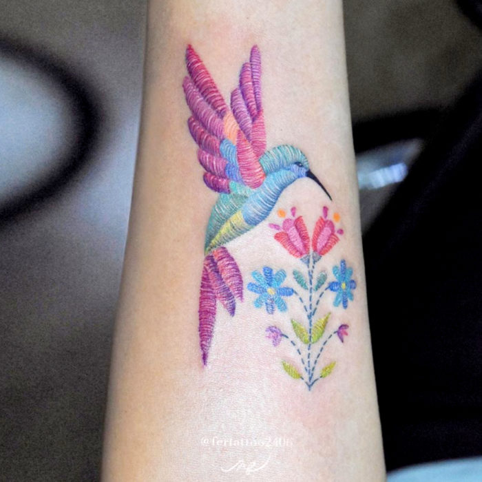 Fernanda Ramírez, tatuadora mexicana crea tatuajes bordados; colibrí con flores en el antebrazo