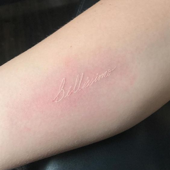 Tatuaje de frase en el brazo con tinta blanca