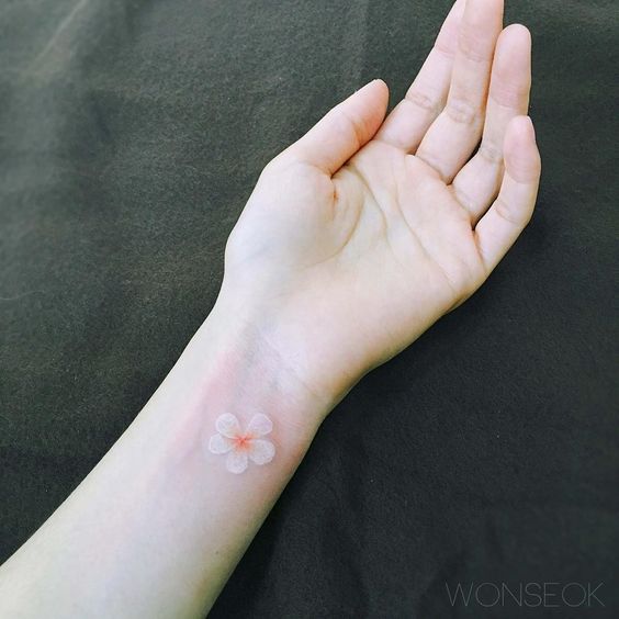 Tatuaje de flor con tinta blanca en el brazo