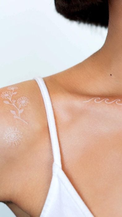 Tatuaje de flores en el hombro con tinta blanca