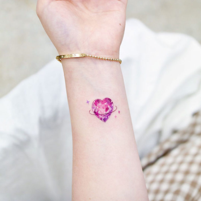 Tatuajes pequeños en la muñeca; corazón rosa de cristal