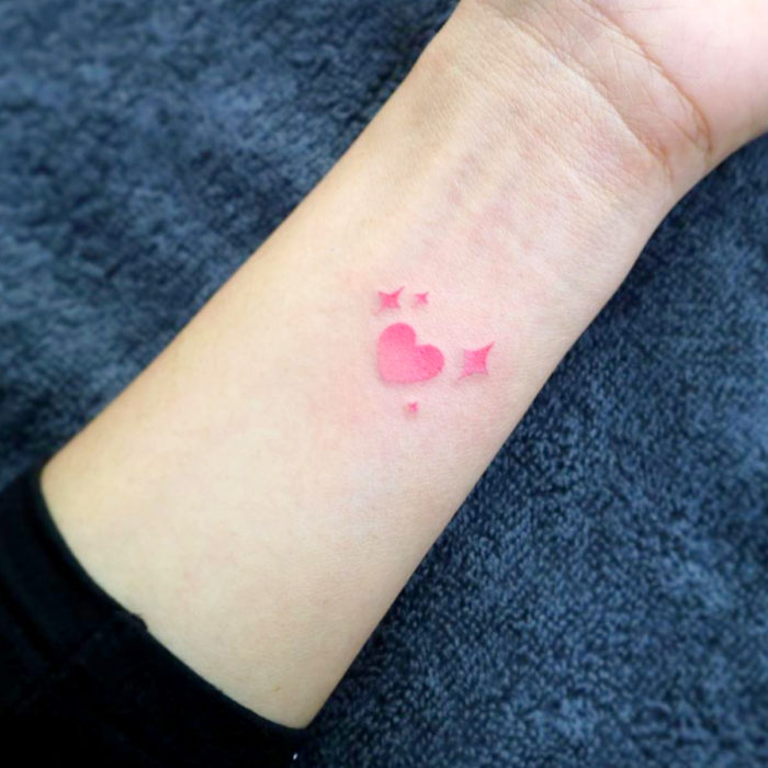 Tatuajes pequeños en la muñeca; corazón rosa con brillos