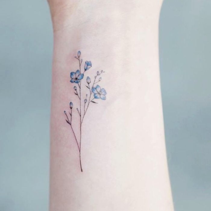 Tatuajes pequeños en la muñeca; flores azules