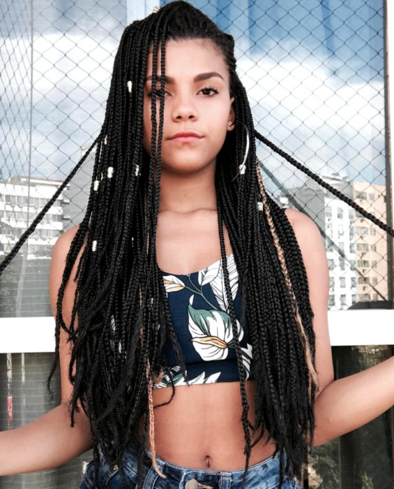 Looks con trenzas africanas; mujer de cabello negro y largo con accesorios y crop top de flores