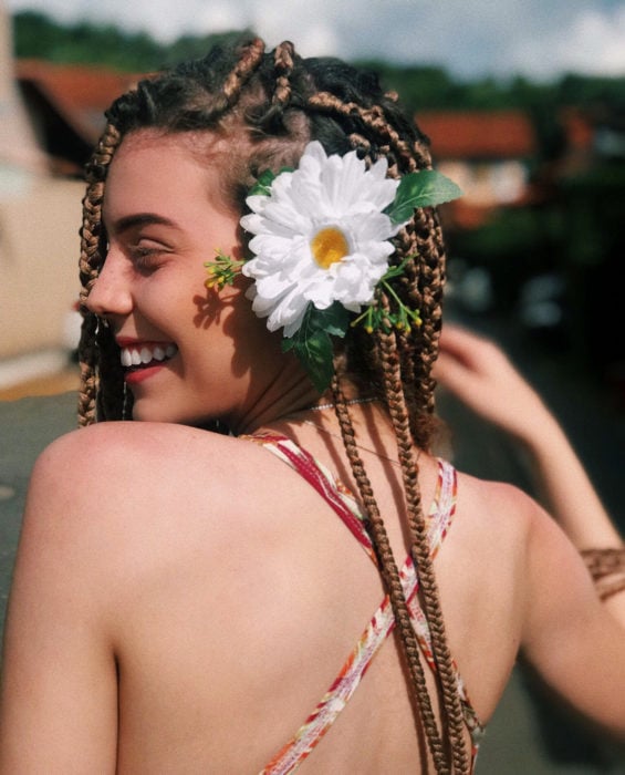 Looks con trenzas africanas; mujer sonriendo, cabello largo y rubio con flores