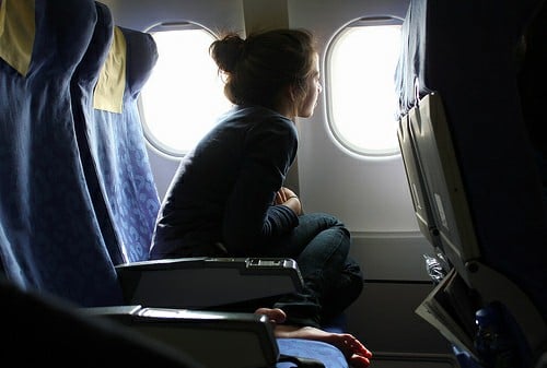 Chica sentada en un avión mirando por la vetana
