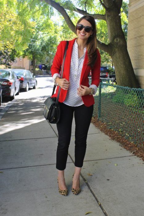 Mujer con saco rojo, pantalón negro y zapatillas en animal print