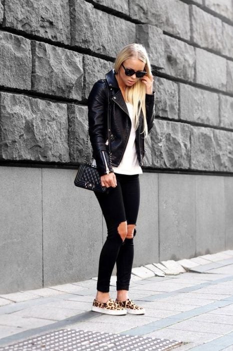 Chica rubia con cabello suelto y outfit negro usa zapatos animal print