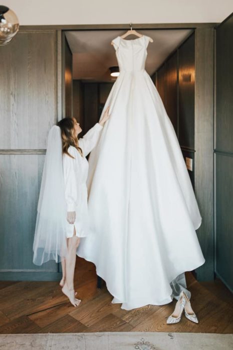 Debby Ryan posando junto a su vestido de boda blanco con diseño plisado 
