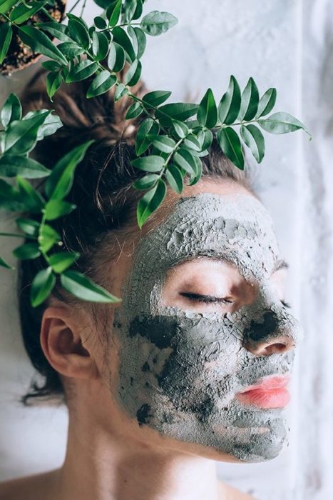 Chica posando de perfil mostrando su rostro con una mascarilla de arcilla verde