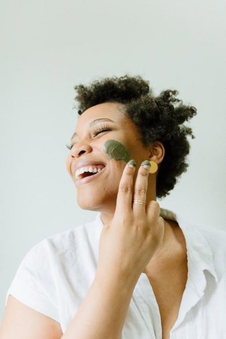 Chica de cabello corto aplicando una mascarilla sobre el rostro