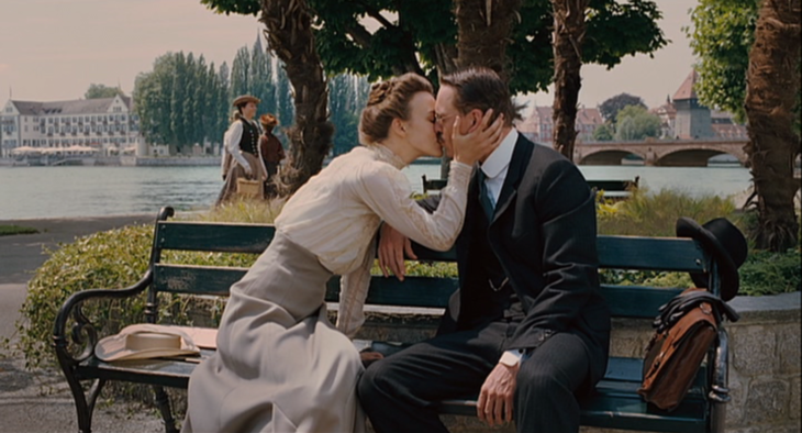 Escena de la película Un método peligoroso, pareja de lso años 30 sentada en una banca del parque besándose 