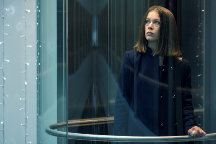 Escena de la serie alemana Bad Banks, una mujer mirando a través d eun vidrio por un pasillo largo