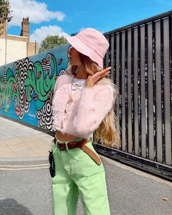 Chica posando para una foto en plebna avenida junto a una pared llena de dibujos