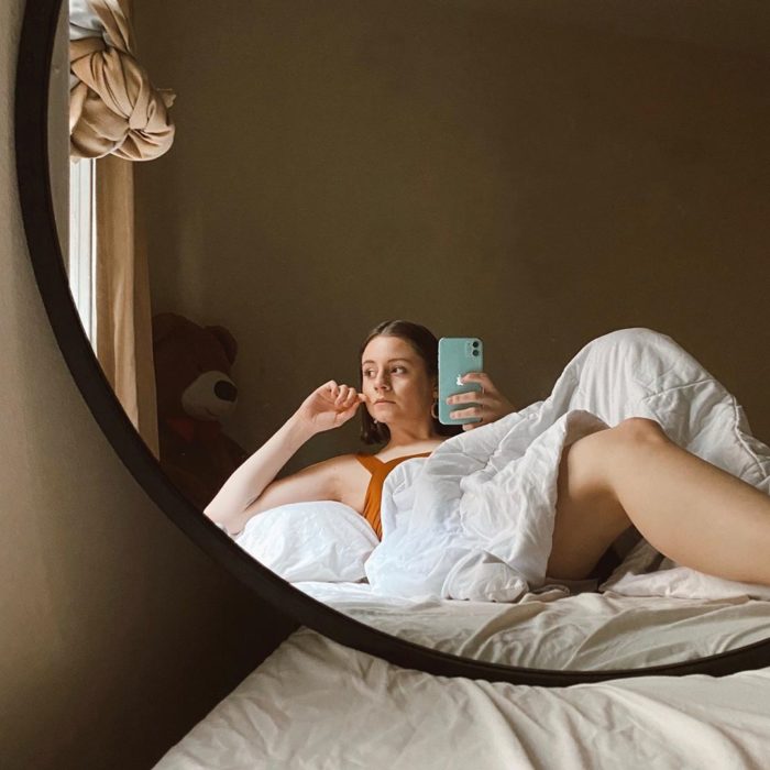 Chica tomando selfie con su celular del refrejo del espejo