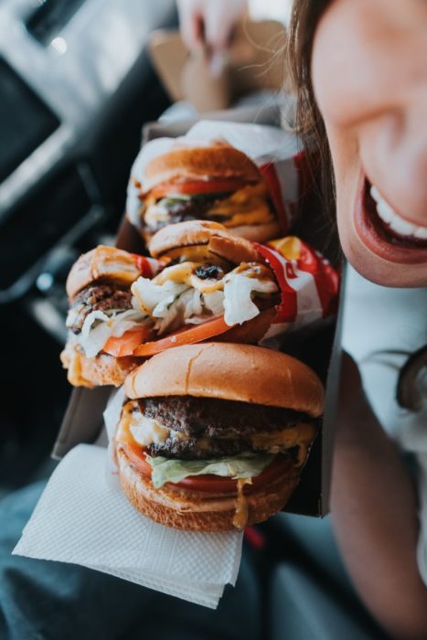 Chica sosteniendo una bandeja con hamburguesas