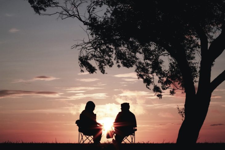 Amigos platicando bajo el árbol en el atardecer