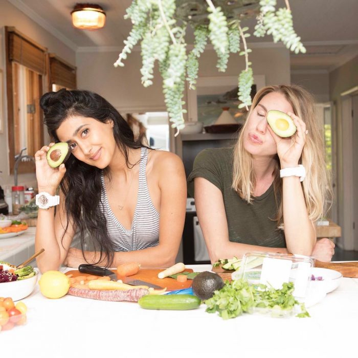 Chicas comiendo aguacates dentro de una cocina blancs