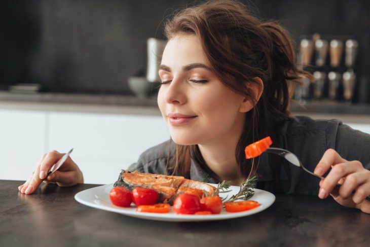 chica comiendo salmón con tomates rojos