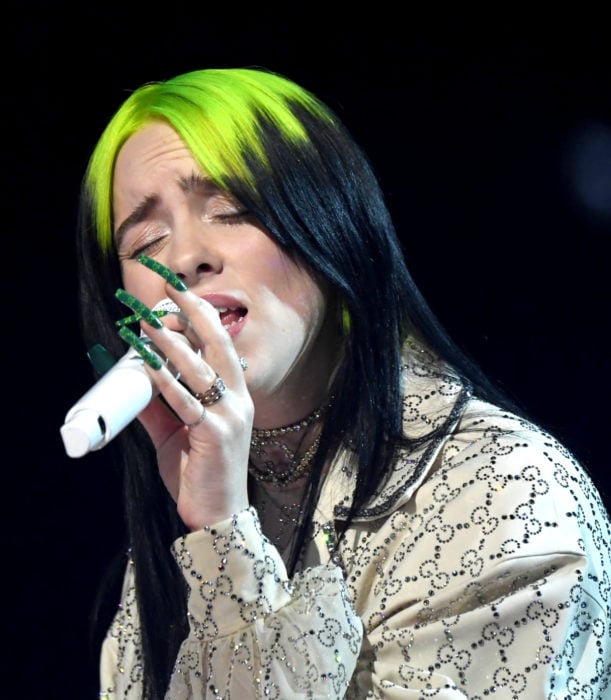 Billie Eilish canrando, cabello verde neón y negro