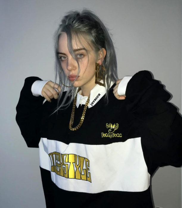 Billie Eilish con cabello gris, peinado en una coleta de caballo, con sudadera oversized