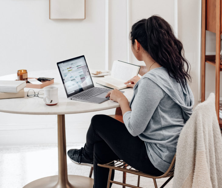 Chica sentada en un escritorio, mirando su laptop, estudiando, haciendo tarea