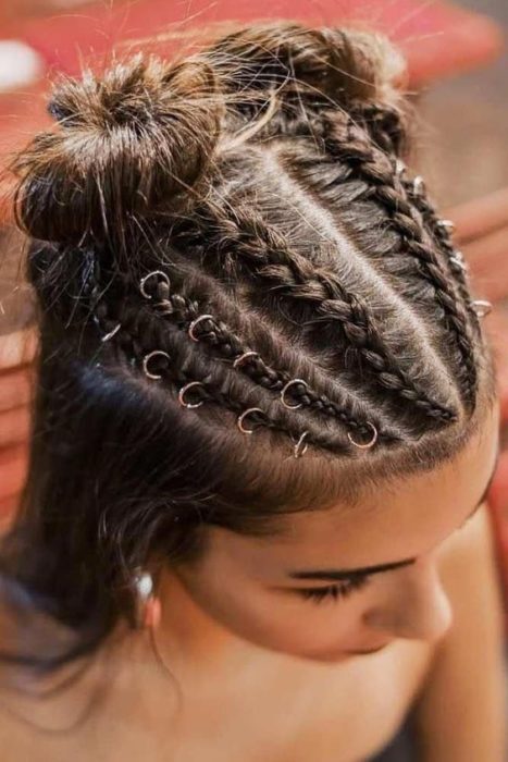 Chica de cabello largo y castaño con argollas en el cabello con trenzas