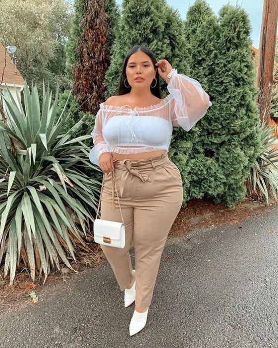 Chica curvy con blusa blanca con transparencias y pantalón beige