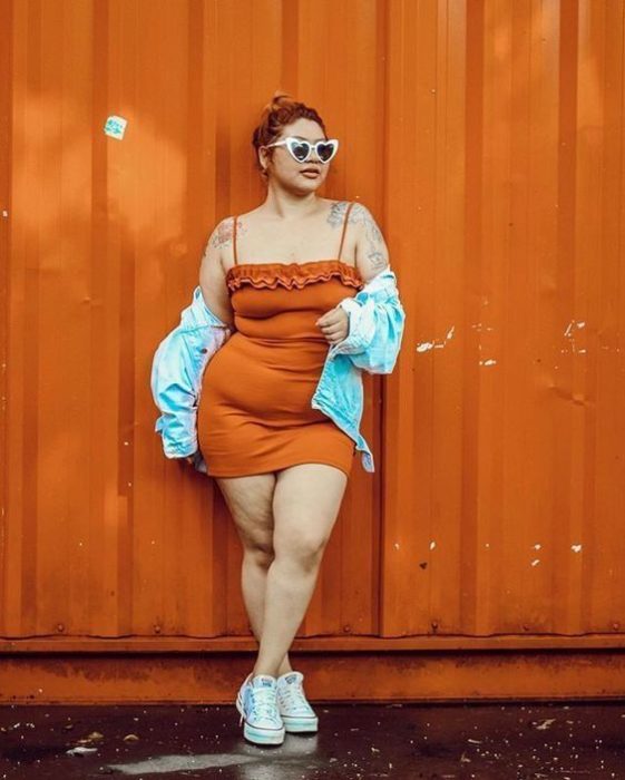 Chica curvy con vestido naranja de tirantes y chamarra de mezclilla