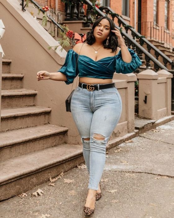 Chica curvy de melena corta con jeans rotos y blusa de satín verde