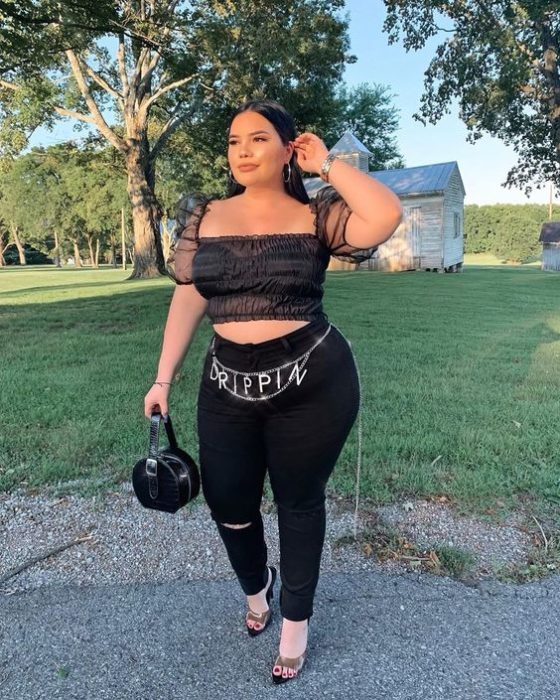 Chica curvy con blusa transparente negra y patanlón negro